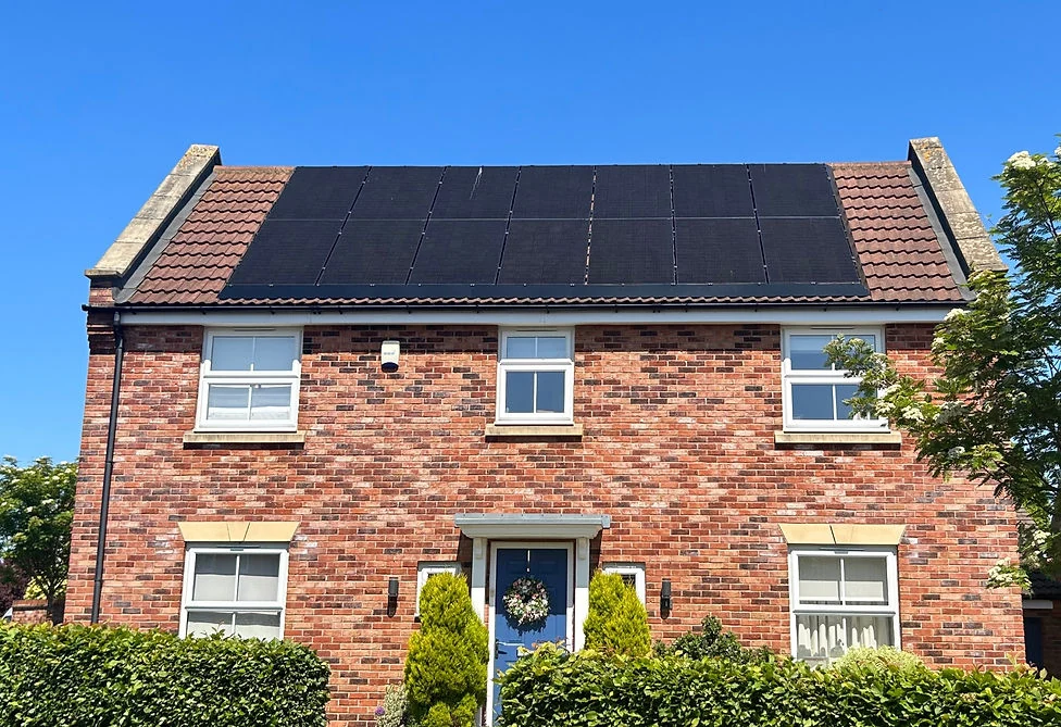 Real UK brick home with black solar panels installed across its tiled roof